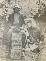 Miner-sitting-on-dynamite-boxes